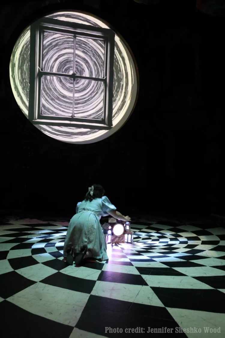Alice beneath a projected spiral window on a swirling checkerboard floor. Photo credit: Jennifer Sheshko Wood.